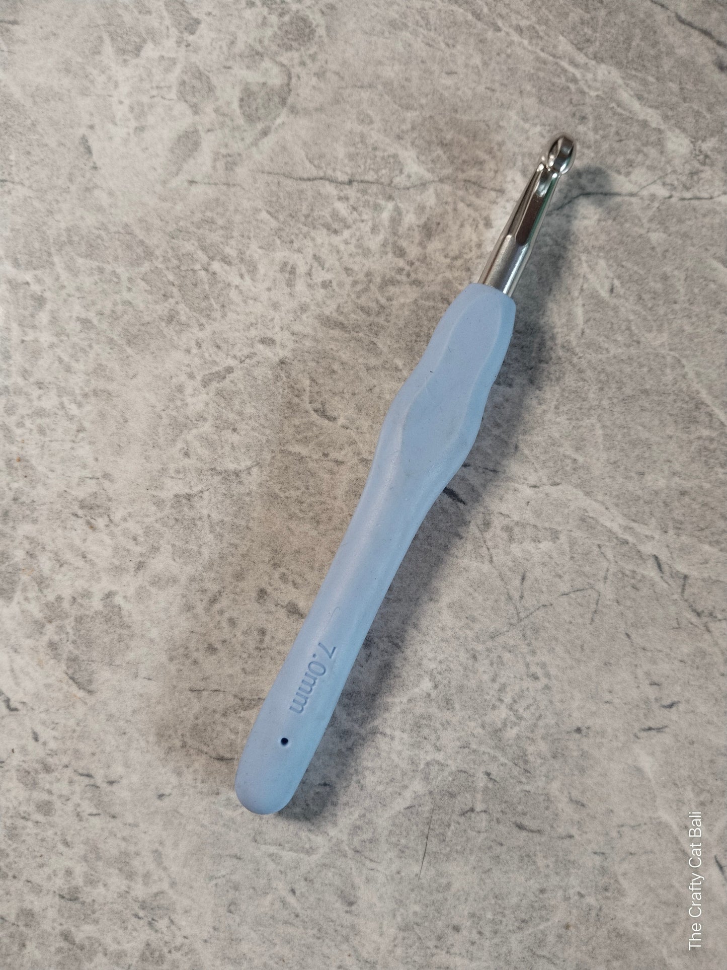 Blue crochet hook on a textured gray surface
